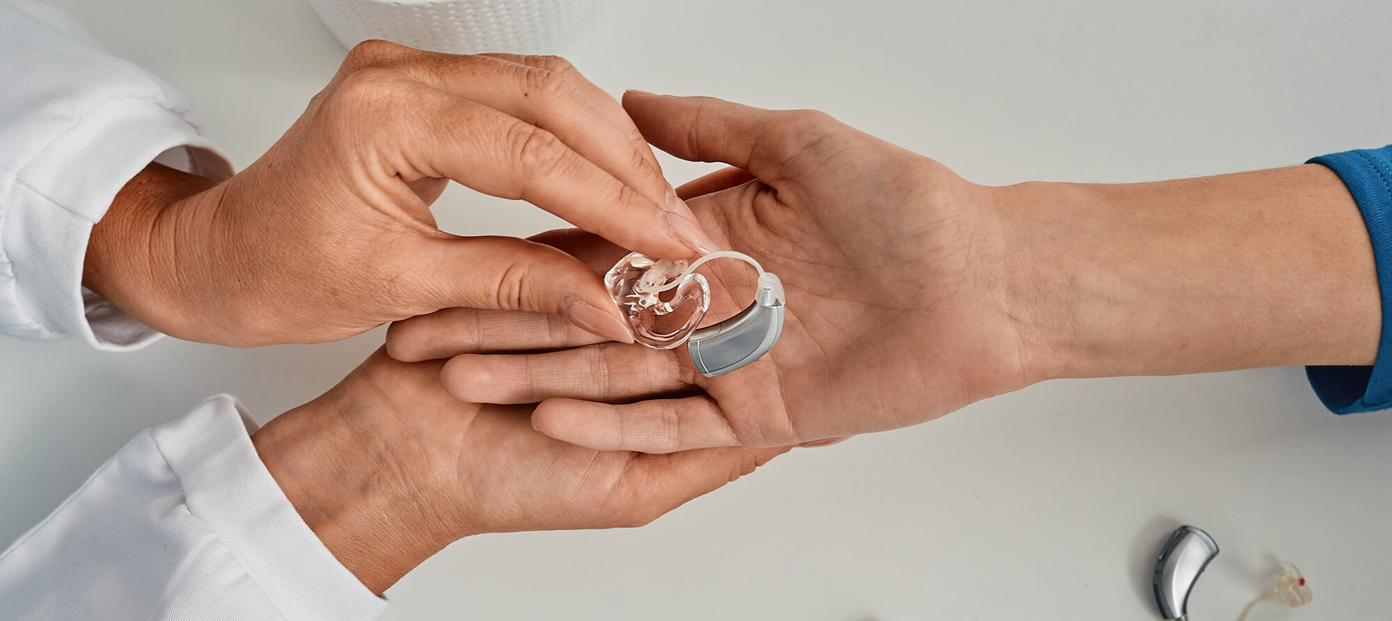 A doctor handing a clear hearing aid to a patient