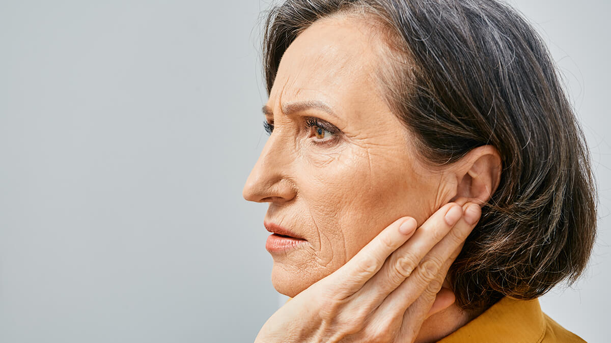 Woman holding her hand up to her ear.