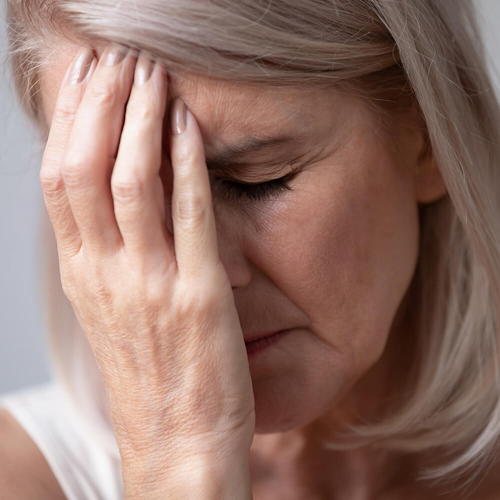 Older woman holding her hand up to her face in pain.